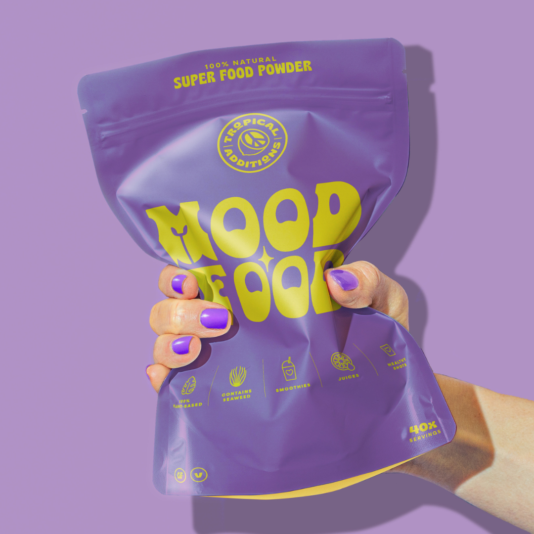 tropical additions superfood blends - mood food mood balancing blend - packet held by hand on purple background